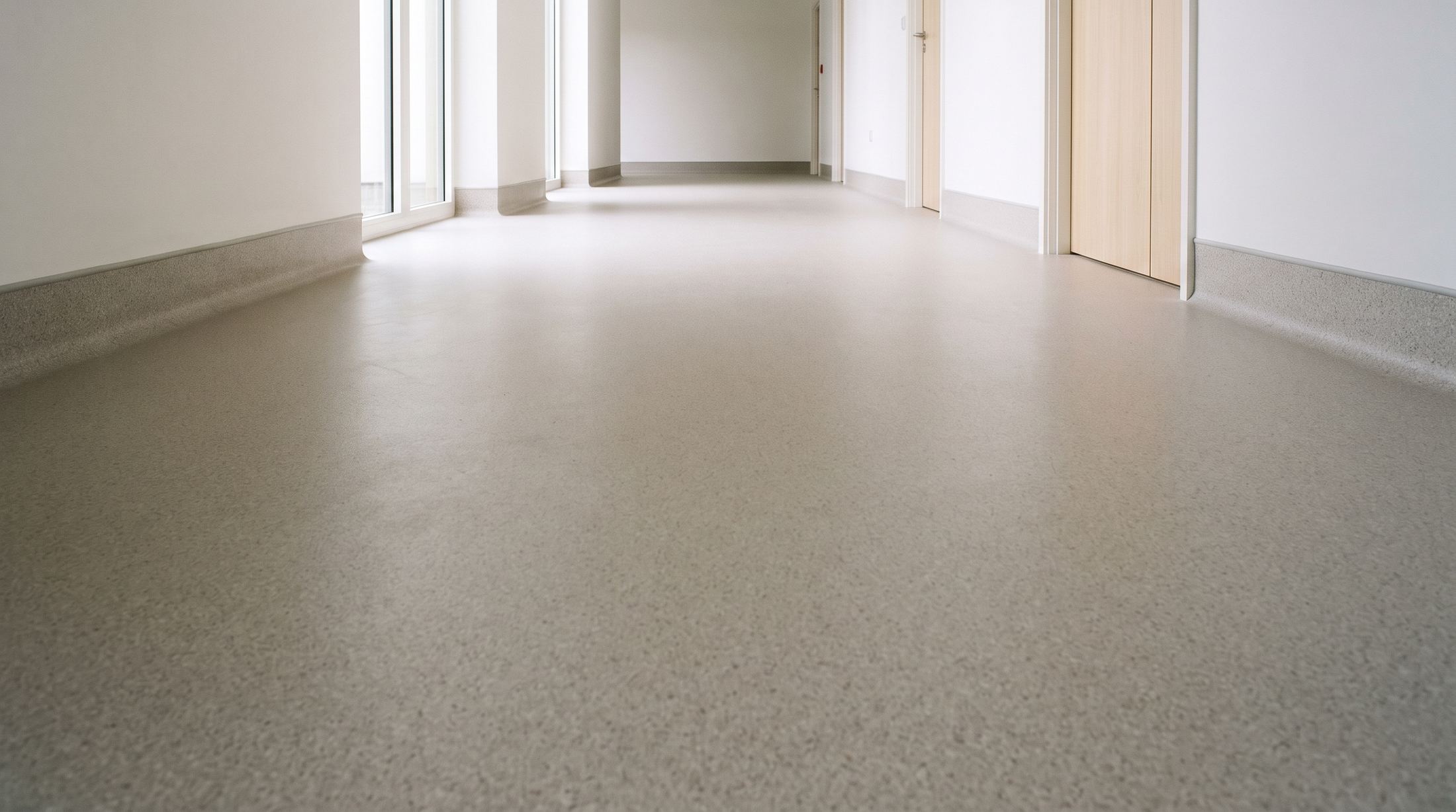 A long, empty corridor with welded speckled sheet vinyl curving up the walls