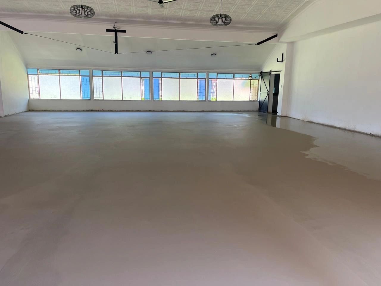 A hall with fresh pale screed under pendant lights