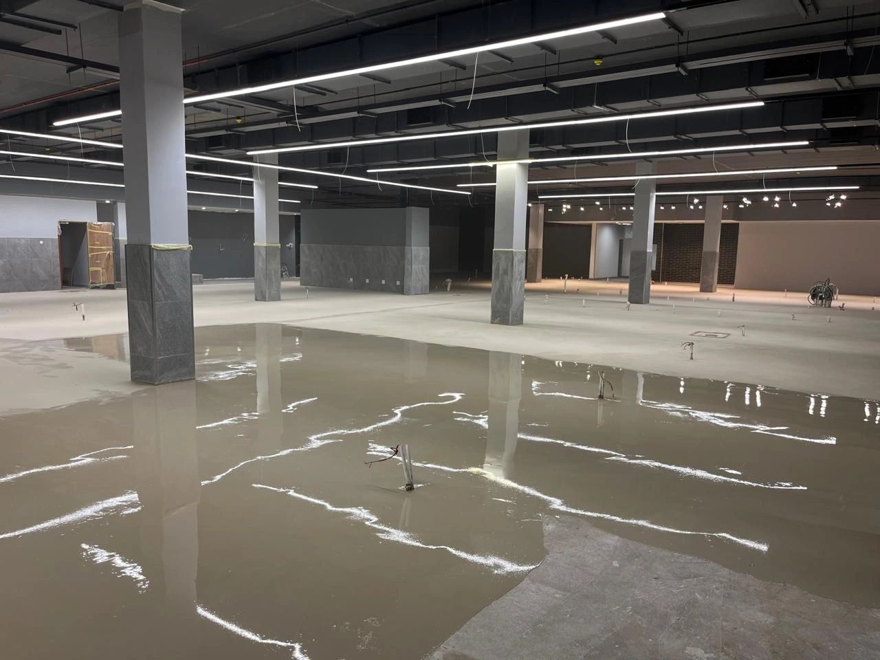 Wet self-levelling compound pooling between columns in a commercial shell